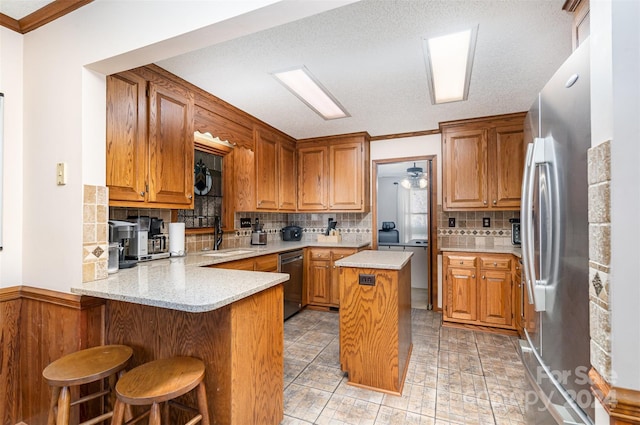 kitchen with decorative backsplash, a center island, kitchen peninsula, and stainless steel appliances