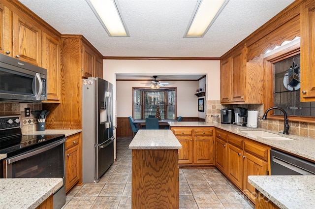 kitchen featuring tasteful backsplash, stainless steel appliances, ceiling fan, sink, and a kitchen island