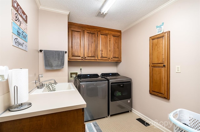 laundry area featuring washer and clothes dryer, cabinets, crown molding, sink, and a textured ceiling