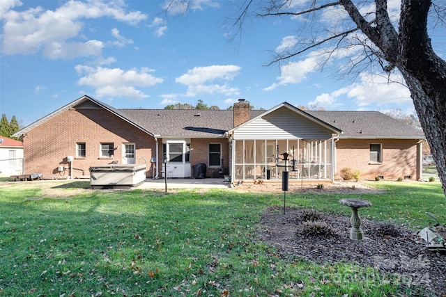 rear view of property featuring a patio area, a sunroom, a yard, and a hot tub