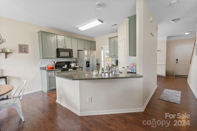 kitchen featuring decorative backsplash, kitchen peninsula, dark wood-type flooring, black appliances, and dark stone countertops