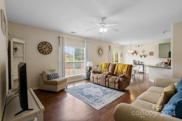 living room featuring ceiling fan with notable chandelier, a textured ceiling, and dark hardwood / wood-style flooring