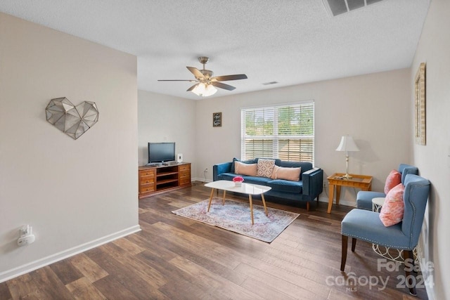 living room with a textured ceiling, ceiling fan, and dark hardwood / wood-style floors