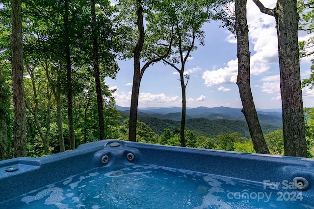 view of pool with a mountain view and a hot tub