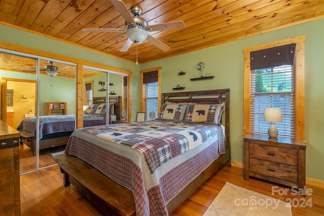 bedroom with ceiling fan, light wood-type flooring, wood ceiling, and multiple closets