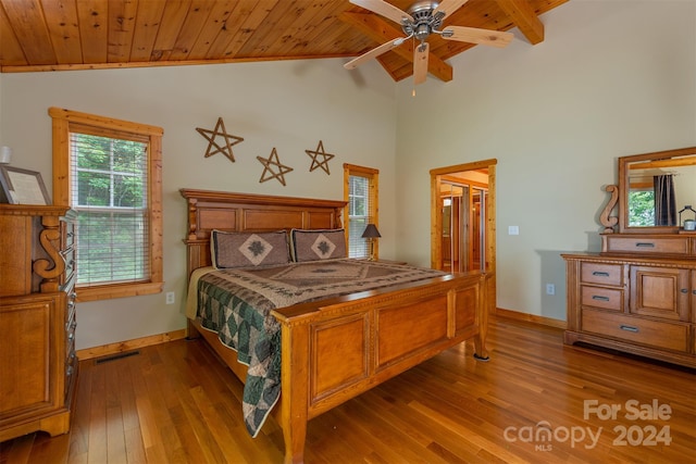 bedroom featuring hardwood / wood-style floors, ceiling fan, vaulted ceiling with beams, and multiple windows