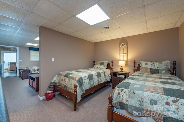 carpeted bedroom featuring a drop ceiling