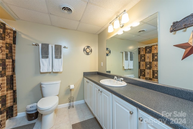 bathroom featuring a paneled ceiling, tile patterned flooring, vanity, and toilet