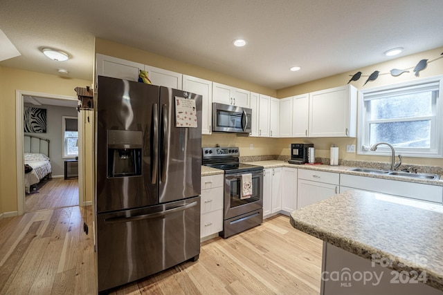 kitchen featuring light wood-type flooring, stainless steel appliances, white cabinetry, and sink