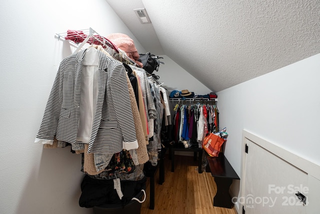 walk in closet featuring light hardwood / wood-style floors and lofted ceiling