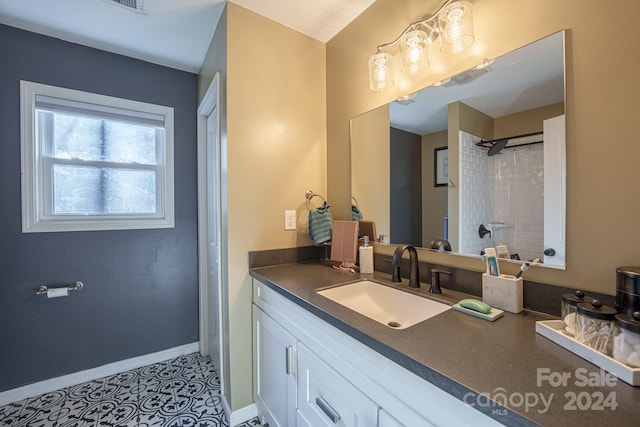 bathroom featuring tile patterned flooring, vanity, and tiled shower