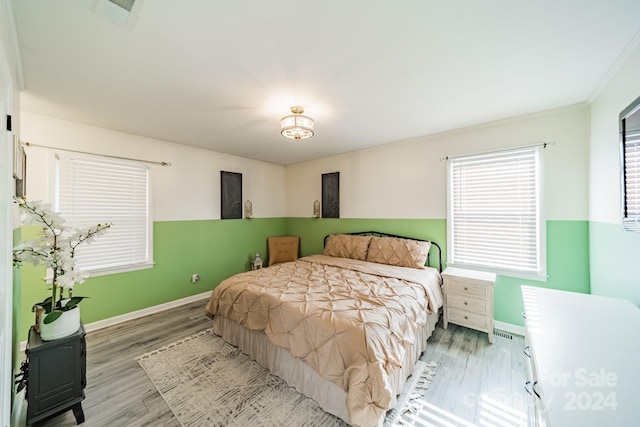 bedroom featuring multiple windows, crown molding, and hardwood / wood-style flooring