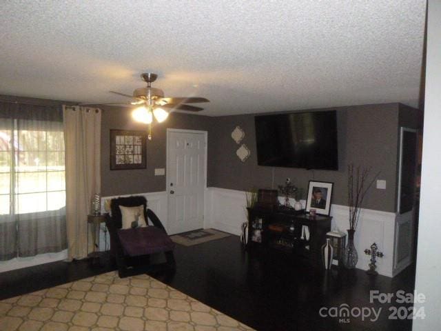 living room featuring ceiling fan and a textured ceiling