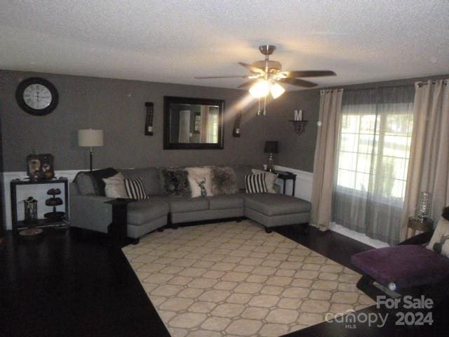 living room featuring ceiling fan and a textured ceiling