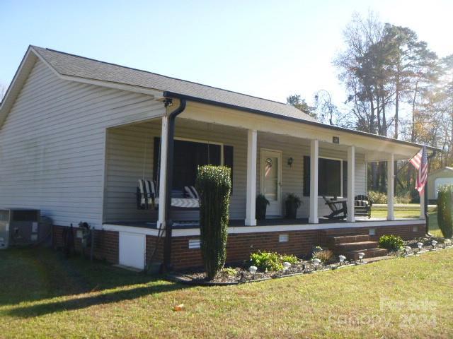 view of front of property with covered porch, central air condition unit, and a front lawn