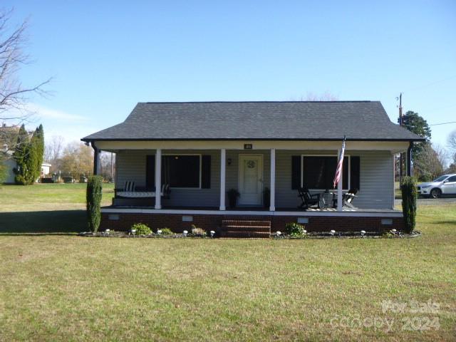 bungalow featuring covered porch and a front lawn