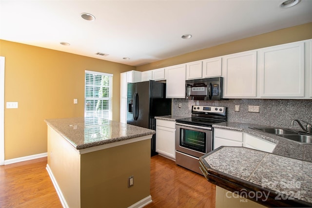 kitchen featuring tasteful backsplash, black appliances, a center island, light hardwood / wood-style floors, and white cabinetry