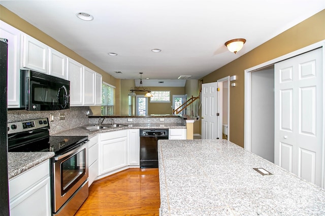 kitchen featuring sink, light hardwood / wood-style flooring, decorative backsplash, white cabinets, and black appliances