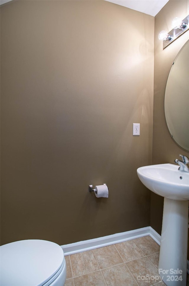 bathroom with toilet, tile patterned floors, and sink