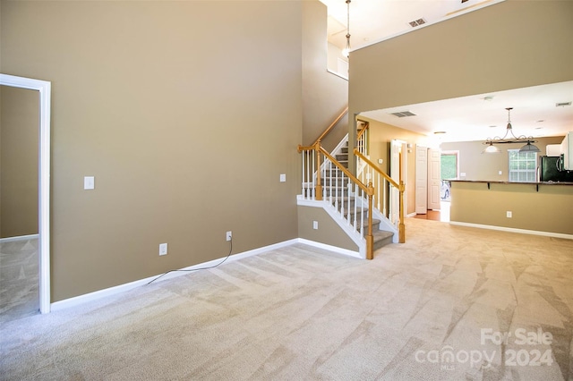 unfurnished living room with light carpet and a high ceiling