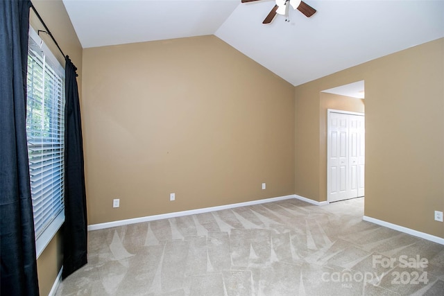 carpeted spare room featuring ceiling fan and vaulted ceiling