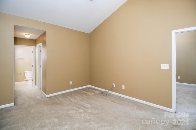 carpeted spare room featuring vaulted ceiling