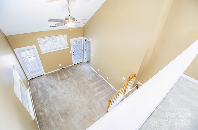 carpeted foyer featuring ceiling fan and high vaulted ceiling