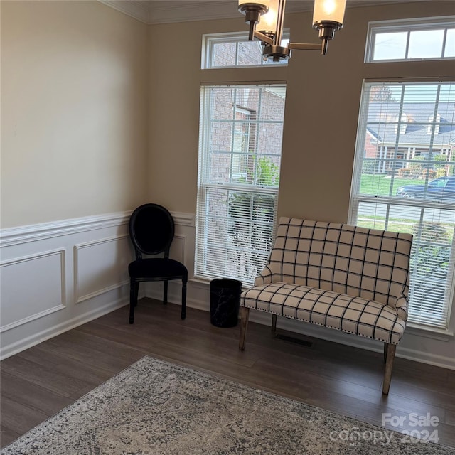 living area with dark hardwood / wood-style flooring, ornamental molding, and a notable chandelier