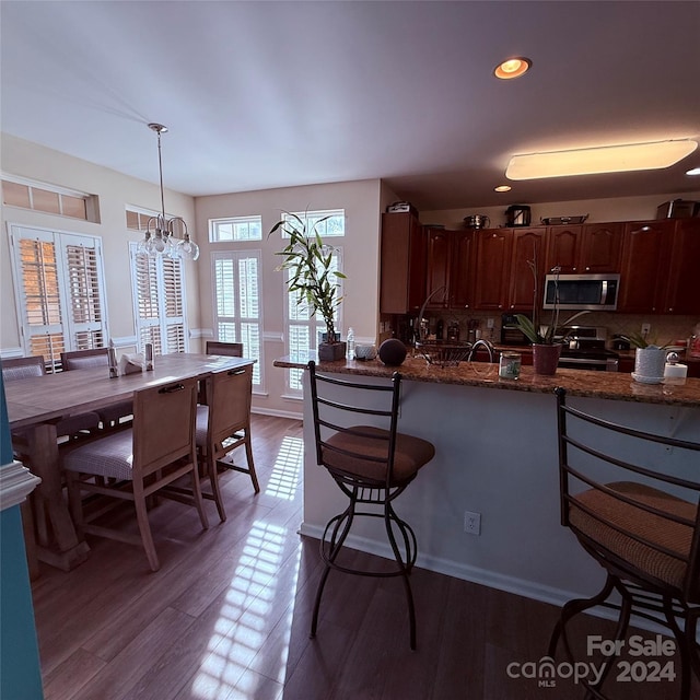 kitchen with hardwood / wood-style floors, decorative backsplash, decorative light fixtures, stainless steel appliances, and a chandelier