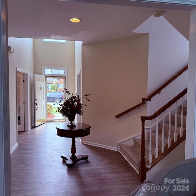 foyer with hardwood / wood-style floors and a towering ceiling