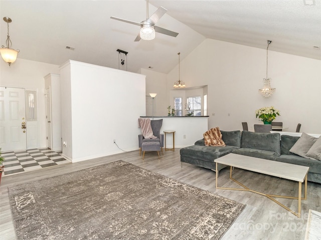 living room with hardwood / wood-style floors, ceiling fan with notable chandelier, and high vaulted ceiling