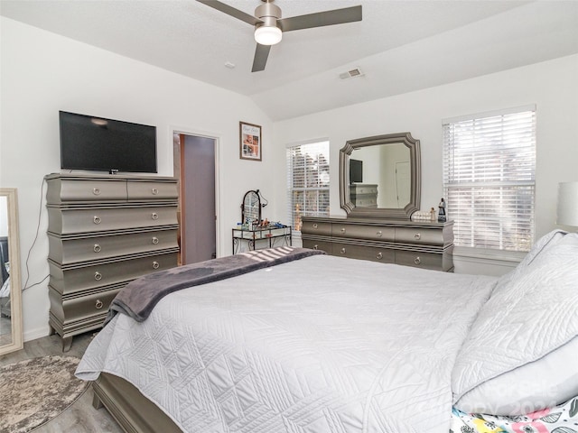 bedroom featuring ceiling fan, light hardwood / wood-style floors, lofted ceiling, and multiple windows