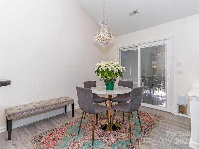 dining space featuring a chandelier, light wood-type flooring, and vaulted ceiling