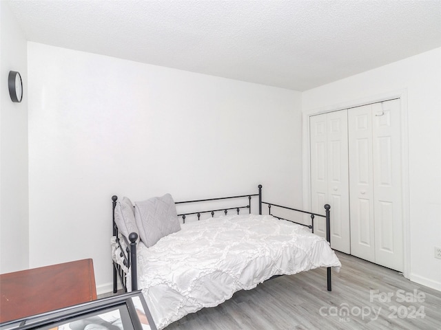 bedroom featuring a closet, light hardwood / wood-style floors, and a textured ceiling