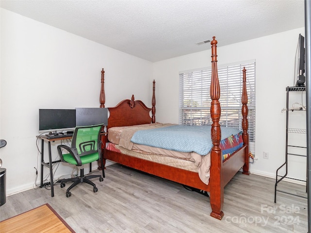 bedroom with hardwood / wood-style floors and a textured ceiling