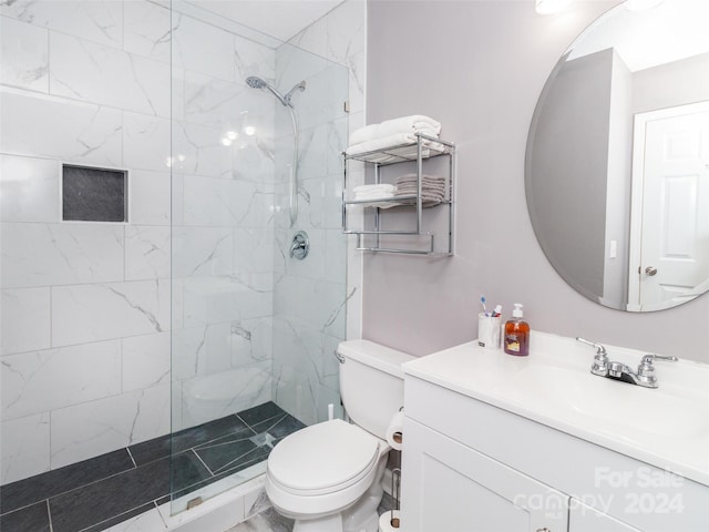 bathroom with a tile shower, vanity, and toilet