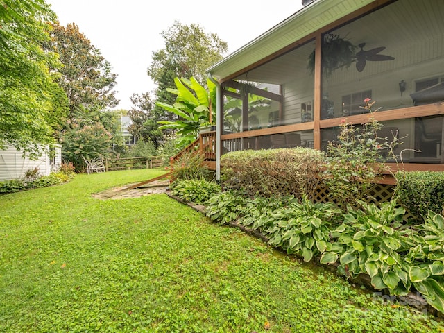 view of yard featuring a sunroom and ceiling fan