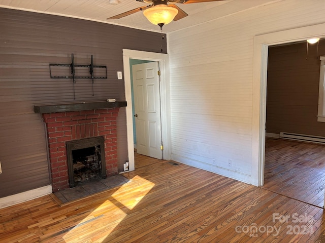 unfurnished living room with a fireplace, hardwood / wood-style floors, ceiling fan, and wood walls