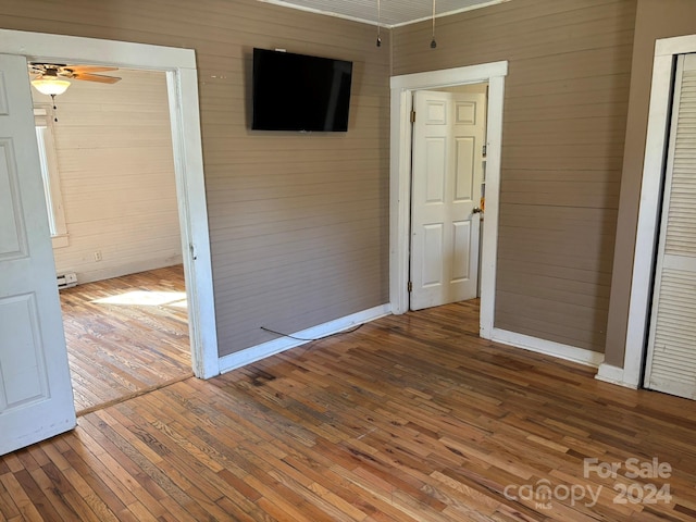 spare room with hardwood / wood-style floors, ceiling fan, and wood walls