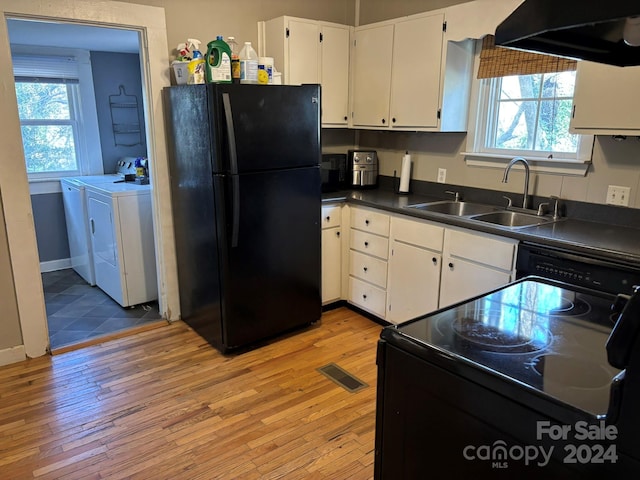 kitchen with black appliances, separate washer and dryer, sink, and light hardwood / wood-style flooring