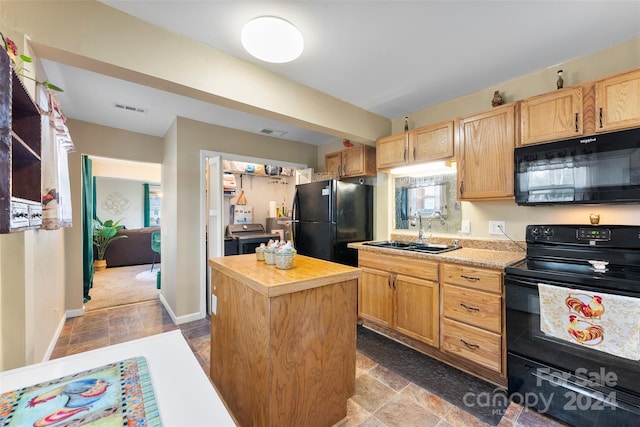 kitchen with sink, wood counters, light brown cabinetry, a kitchen island, and black appliances