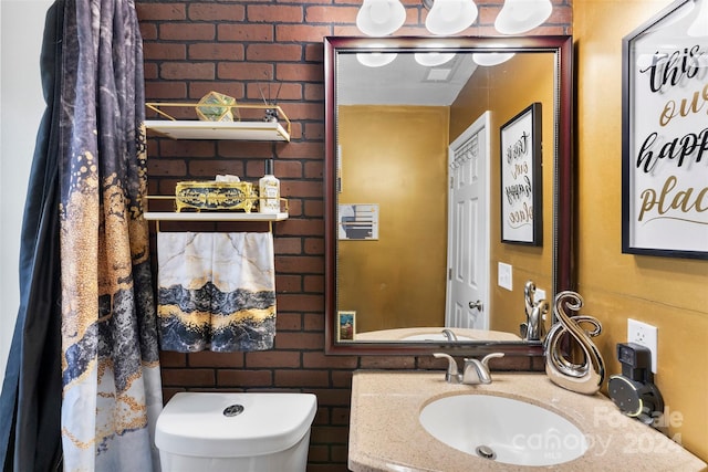 bathroom with toilet, sink, and brick wall