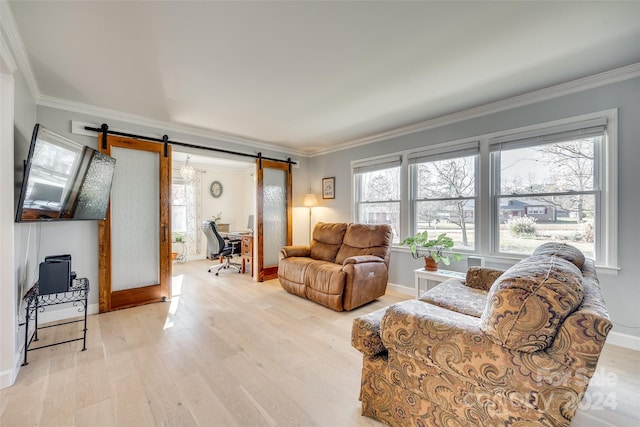 living room with a barn door, a wealth of natural light, crown molding, and light hardwood / wood-style floors