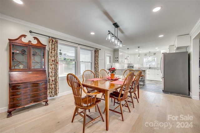 dining room with light hardwood / wood-style floors and crown molding