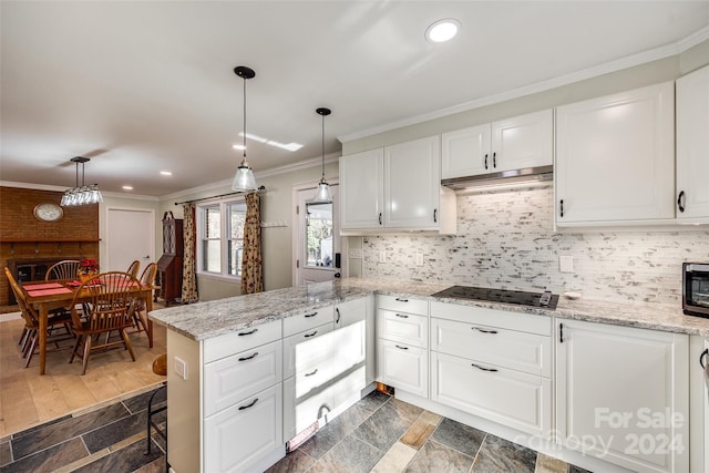 kitchen featuring kitchen peninsula, black cooktop, crown molding, pendant lighting, and white cabinetry