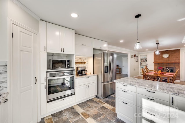 kitchen featuring appliances with stainless steel finishes, white cabinetry, hanging light fixtures, and ornamental molding