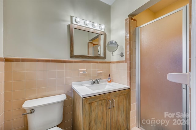 bathroom with vanity, toilet, walk in shower, and tile walls