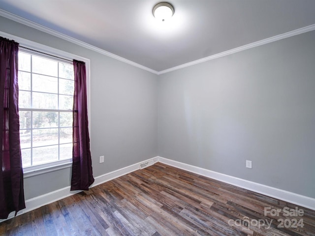 spare room featuring ornamental molding and dark wood-type flooring