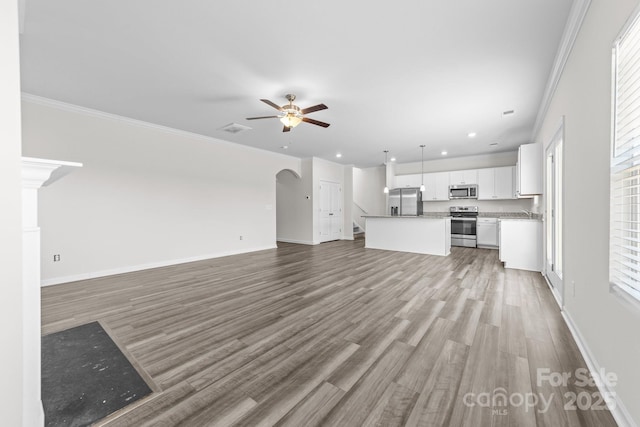 unfurnished living room featuring hardwood / wood-style flooring, crown molding, plenty of natural light, and ceiling fan