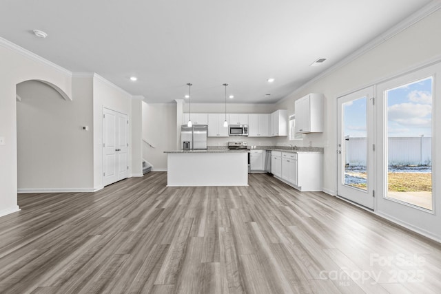 kitchen with decorative light fixtures, white cabinets, a center island, stainless steel appliances, and crown molding